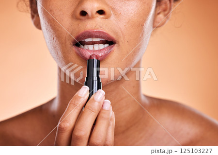 Lipstick, black woman and cosmetics for skincare, natural beauty and wellness against brown studio background. Makeup, female and girl with lip gloss for soft lips, mouth and smooth facial for lady. 125103227