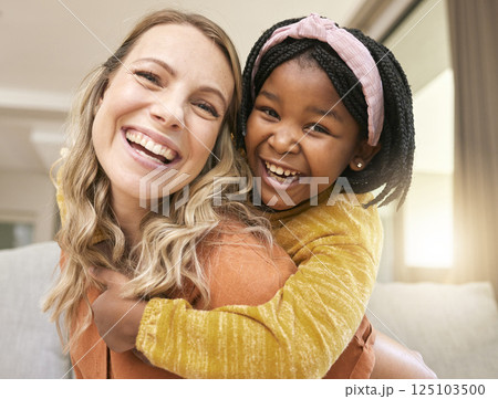Portrait, love and family with an adopted girl and foster mother bonding in the living room of their home. Face, smile and piggyback with a woman and daughter in their house together with a smile 125103500