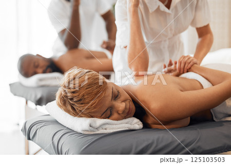 Massage, table and relax black woman or couple at a spa with physical therapy worker hands for stress, muscle and pain health, wellness and healing. Peace, calm and african people back treatment 125103503