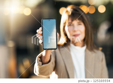 Woman, hand and phone mockup on bokeh background for mobile advertising, marketing or sale in the outdoors. Hands of female showing wireless technology smartphone for communication on blue chromakey Woman, hand and phone mockup on bokeh background for mobile advertising, marketing or sale in the outdoors. Hands of female showing wireless technology smartphone for communication on blue chromakey 125103554