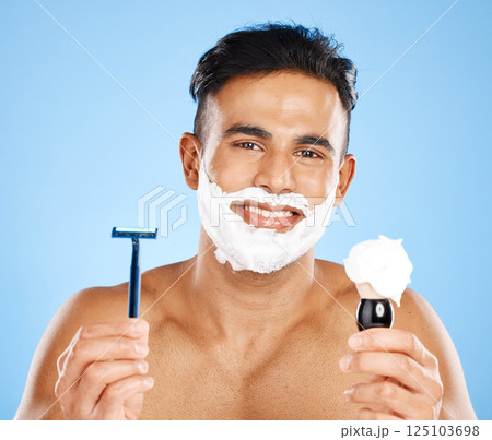 Man, razor and shaving cream for skincare, grooming or facial treatment against a blue studio background. Portrait of a male beard with smile holding cosmetics for shave, beauty or hygiene on mockup 125103698