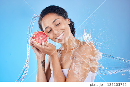 Shower, water and grapefruit with a model black woman in studio on a blue background with a splash for hygiene. Health, water splash and skincare with an attractive young female holding natural fruit 125103753