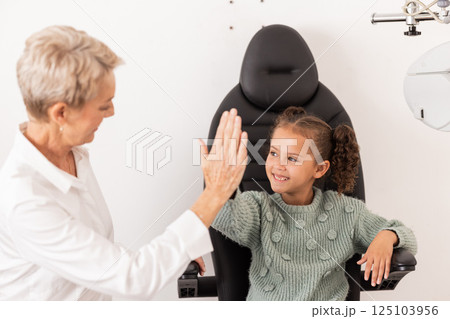 High five, optometrist and children with a girl and woman in an optometry appointment for prescription lenses. Motivation, eye test and success with a female child and optician in celebration 125103956