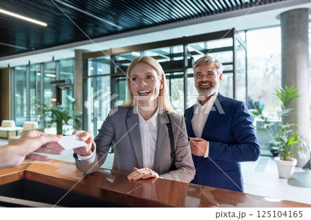 Man and woman talking at office reception counter while handing key card Man and woman talking at office reception counter while handing key card 125104165