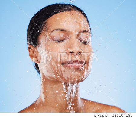 Woman, shower and water splash on face for skincare hydration or clean hygiene against blue studio background. Female in facial wash with water to hydrate or cleanse for hygienic body care treatment Woman, shower and water splash on face for skincare hydration or clean hygiene against blue studio background. Female in facial wash with water to hydrate or cleanse for hygienic body care treatment 125104186