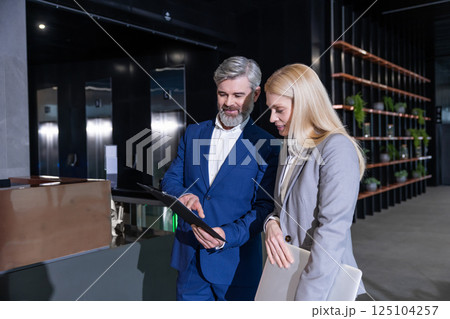 Businesswoman and manager standing in office corridor discussing company development Businesswoman and manager standing in office corridor discussing company development 125104257