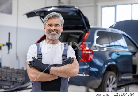 Man in uniform working indoors in garage Man in uniform working indoors in garage 125104384