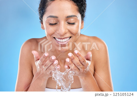 Splash, water and black woman for facial skincare, cleaning or healthy glow promotion on blue studio mockup. Beauty, skin care and cosmetics model with water splash in her hands for natural face wash 125105124