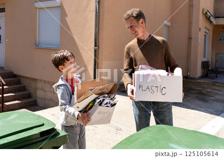 Father and son talk while holding boxes with sorted waste outdoors 125105614