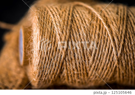 Natural jute twine roll, burlap on black background. Supplies and tools for handmade hobby leisure Natural jute twine roll, burlap on black background. Supplies and tools for handmade hobby leisure 125105646