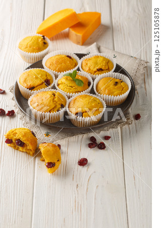 Delicious pumpkin cranberry muffins are made with pumpkin puree and dried cranberries closeup on the plate. Vertical Delicious pumpkin cranberry muffins are made with pumpkin puree and dried cranberries closeup on the plate. Vertical 125105878