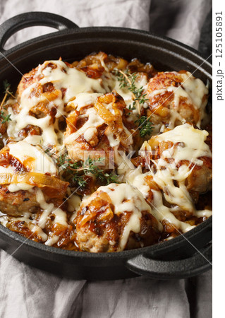 French onion meatballs smothered in rich caramelized onion gravy and topped with melty Gruyere cheese closeup on the pan. Vertical French onion meatballs smothered in rich caramelized onion gravy and topped with melty Gruyere cheese closeup on the pan. Vertical 125105891