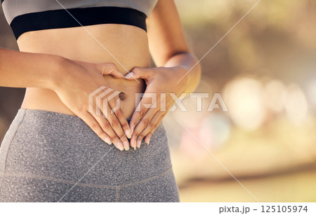 Weightloss, hands and heart shape on stomach for body positivity during diet, exercise and training. Wellness, health and closeup of woman with self love gesture on tummy while doing outdoor workout. Weightloss, hands and heart shape on stomach for body positivity during diet, exercise and training. Wellness, health and closeup of woman with self love gesture on tummy while doing outdoor workout. 125105974
