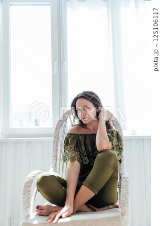 Brunette woman smiling sitting on a chair in a room 125106117