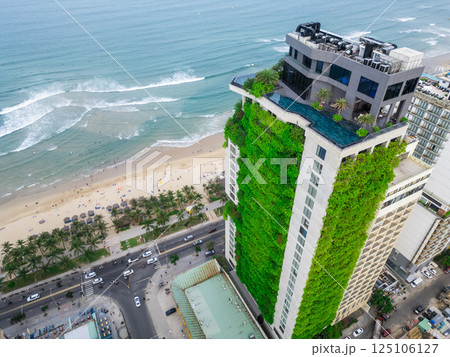 eco friendly green building with vertical garden near ocean, city harmony concept, sustainable architecture and urban nature balance 125106127