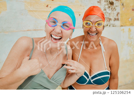 Swimming, vacation and portrait of senior friends with goggles and swim caps ready for pool. Happiness, smile and elderly women at water aerobics class while on retirement holiday in Bali Indonesia. 125106254