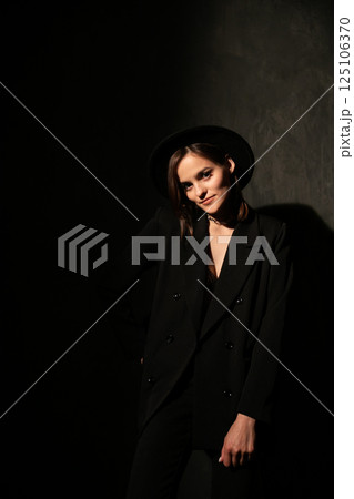 woman in black jacket and hat on dark background woman in black jacket and hat on dark background 125106370