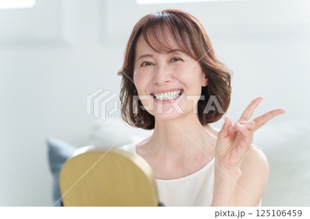 スキンケアするシニア女性(ピースサイン) スキンケアするシニア女性(ピースサイン) 125106459