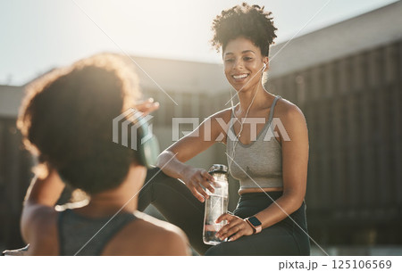 Fitness, headphones and black women or friends in city on break with water bottle and talking. Health, wellness and people resting while streaming music, radio or podcast after running or training. Fitness, headphones and black women or friends in city on break with water bottle and talking. Health, wellness and people resting while streaming music, radio or podcast after running or training. 125106569