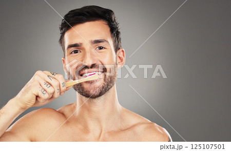 Brushing teeth, bamboo and man in studio for dental, dentist and mouth wellness with product promotion on mockup space. Model portrait with wood and eco friendly toothbrush for mint fresh breath Brushing teeth, bamboo and man in studio for dental, dentist and mouth wellness with product promotion on mockup space. Model portrait with wood and eco friendly toothbrush for mint fresh breath 125107501