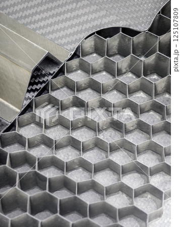 Detailed view of layered honeycomb structure made from metal and carbon fiber showcasing inventive engineering design Detailed view of layered honeycomb structure made from metal and carbon fiber showcasing inventive engineering design 125107809