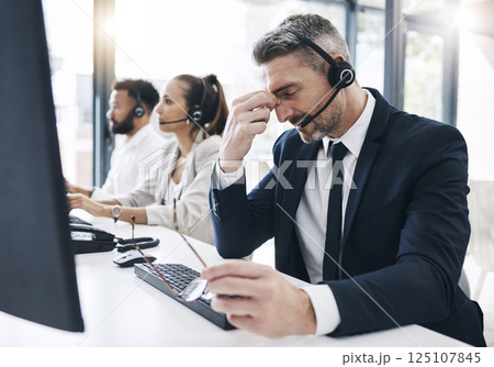 Call center, customer service and man with headache, stress and tired of working in office. Burnout, crm and frustrated male telemarketing consultant in customer support on call with difficult client Call center, customer service and man with headache, stress and tired of working in office. Burnout, crm and frustrated male telemarketing consultant in customer support on call with difficult client 125107845