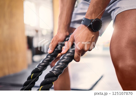 Hands, fitness and battle rope with a sports man training for cardio or endurance in a gym workout. Grip, heavy ropes and exercise with a male athlete holding equipment for a healthy, strong body Hands, fitness and battle rope with a sports man training for cardio or endurance in a gym workout. Grip, heavy ropes and exercise with a male athlete holding equipment for a healthy, strong body 125107870
