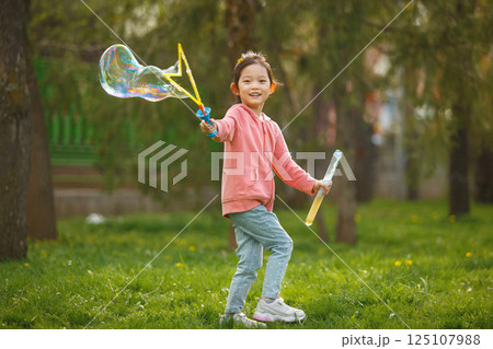 Happy Asian Girl Blowing Bubbles in Park on Sunny Day Happy Asian Girl Blowing Bubbles in Park on Sunny Day 125107988