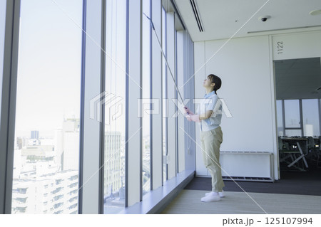 窓ガラスをスクイジーで拭く若い女性清掃員　撮影協力：学校法人電波学園 東京電子専門学校 125107994