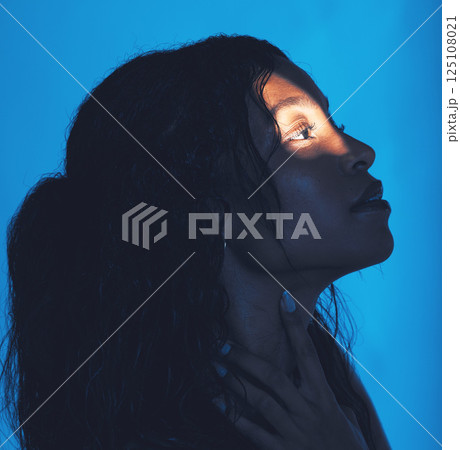 Spotlight, model and woman for skincare, face and cosmetics with blue studio background. Makeup, natural beauty and light reflection on young female, girl and from Mexico for fresh spa treatment 125108021