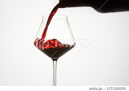 Red wine is poured from bottle into transparent glass. Red wine is poured from bottle into transparent glass. 125108030