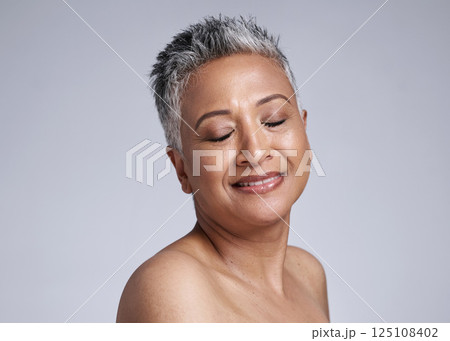 Mature woman, face and skincare glow on gray studio background with makeup cosmetics, dermatology wellness and mockup. Smile, happy or Indian beauty model with healthy facial collagen and self care 125108402