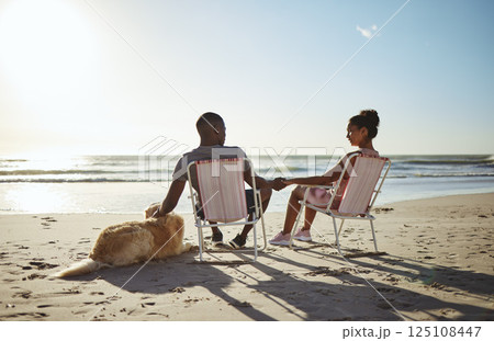 Black couple, dog and sunset beach while on chair to relax on vacation holding hands for love, care and trust by ocean for quality time. Pet with man and woman in healthy marriage on holiday by sea Black couple, dog and sunset beach while on chair to relax on vacation holding hands for love, care and trust by ocean for quality time. Pet with man and woman in healthy marriage on holiday by sea 125108447