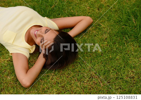 Happy woman relax on park grass, garden and nature, freedom or rest on summer lawn with mockup. Above of young girl lying on green field outdoor in sunshine for calm, peace and mental health wellness 125108831
