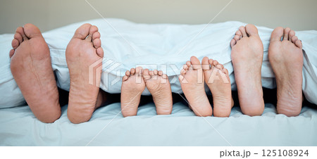 Family, feet and bed in morning for relax, calm and sleeping in bedroom together. Mother, father and young child resting in morning, dreaming and weekend nap or relaxing holiday in family home 125108924