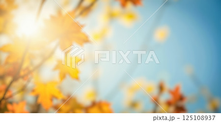 Blurry autumn background, vibrant orange leaves, sunny day, soft focus, nature scene, warm sunlight, blue sky, seasonal glow, dreamy atmosphere, outdoor setting 125108937