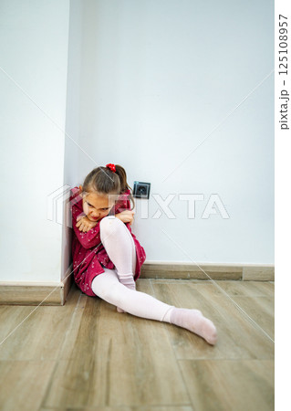 Little girl seeking comfort in a corner, finding solace on a calm afternoon while wearing a vibrant dress and thoughtful expression Little girl seeking comfort in a corner, finding solace on a calm afternoon while wearing a vibrant dress and thoughtful expression 125108957
