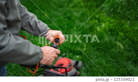 Maintenance of an electric lawn mower highlights the importance of garden care in springtime landscaping Maintenance of an electric lawn mower highlights the importance of garden care in springtime landscaping 125109021