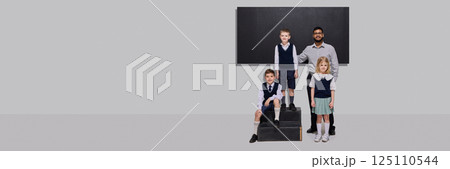 Smiling teacher standing proudly with three students in school uniforms in front of chalkboard. 125110544