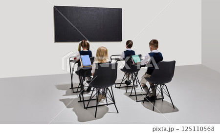 Students, children sitting attentively facing chalkboard during classroom activity, ready for learning and interaction. 125110568