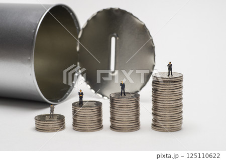 開けられた缶型の貯金箱と積み上げたコイン 125110622