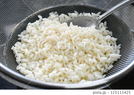 Steamed rice in a mesh strainer colander. Food preparation concept. Steamed rice in a mesh strainer colander. Food preparation concept. 125111425