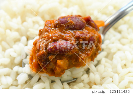 Chilli con carne with rice on spoon. Traditional Mexican food. Chilli con carne with rice on spoon. Traditional Mexican food. 125111426