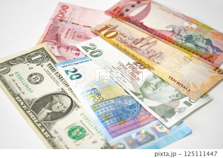 One dollar, 20 euro, 20 Turkish lira, 10 euro, 100 thai baht and 1 bahraini dinar on the table. 125111447
