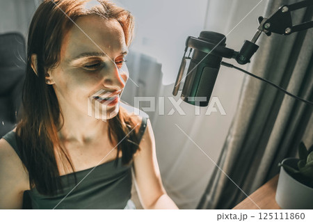 Woman recording a podcast on her computer with microscope. Female podcaster making audio podcast from her home studio. Woman recording a podcast on her computer with microscope. Female podcaster making audio podcast from her home studio. 125111860