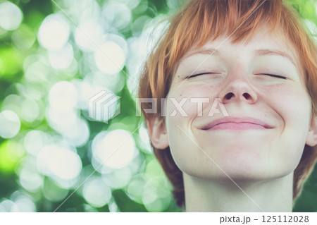 A beautiful woman with shiny face with few wreckles, smiling, eyes closed, enjoying life 125112028