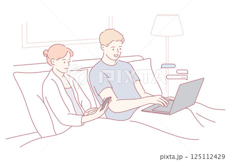 Enjoying a Cozy Evening Together A Couple Engaged with Tech and Devices While in Bed 125112429
