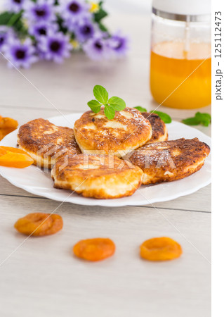 Homemade cheese pancakes with a delicate texture and aromatic dried apricots Homemade cheese pancakes with a delicate texture and aromatic dried apricots 125112473