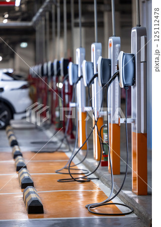 EV charging station and electric car, Electric car charging station for charge EV battery, Plug for vehicle with electric engine, EV charger clean energy, Charging point at car parking lot. EV charging station and electric car, Electric car charging station for charge EV battery, Plug for vehicle with electric engine, EV charger clean energy, Charging point at car parking lot. 125112478