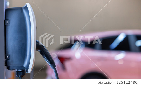 EV charging station and electric car, Electric car charging station for charge EV battery, Plug for vehicle with electric engine, EV charger clean energy, Charging point at car parking lot. 125112480